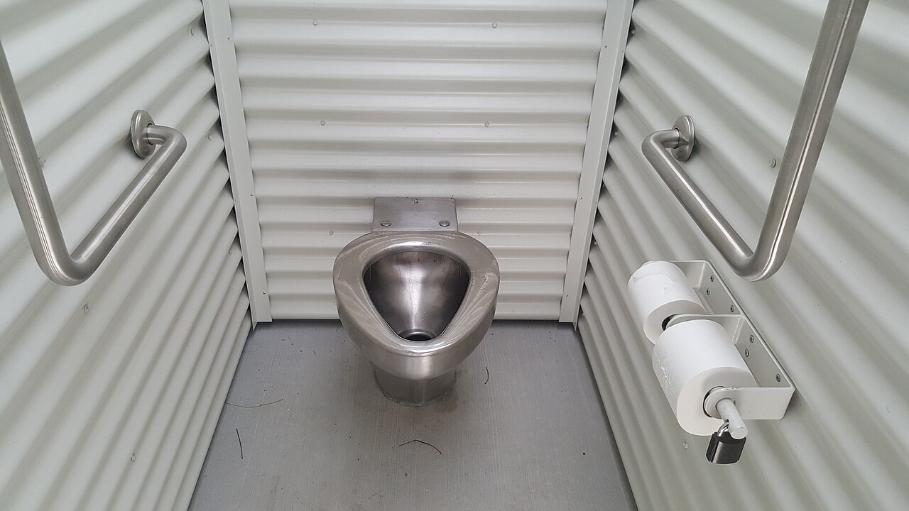Een toilet met een beugel aan weerszijden in een smalle cabine