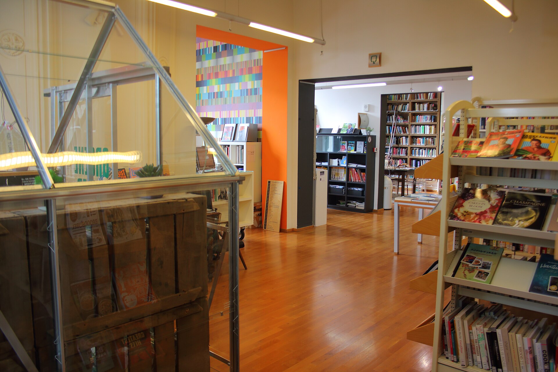 Het interieur van een openbare bibliotheek met boekenrekken, een oranje wand en een houten vloer