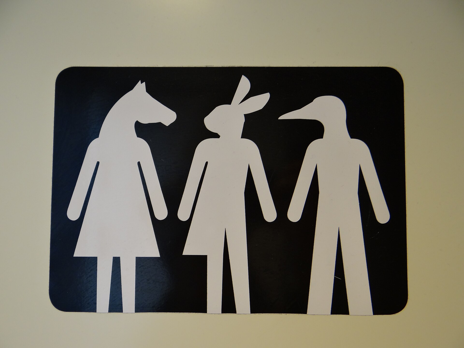 Een toiletbordje met drie pictogrammen: een figuur met een paardenhoofd, een met konijnenoren en een met een vogelkop