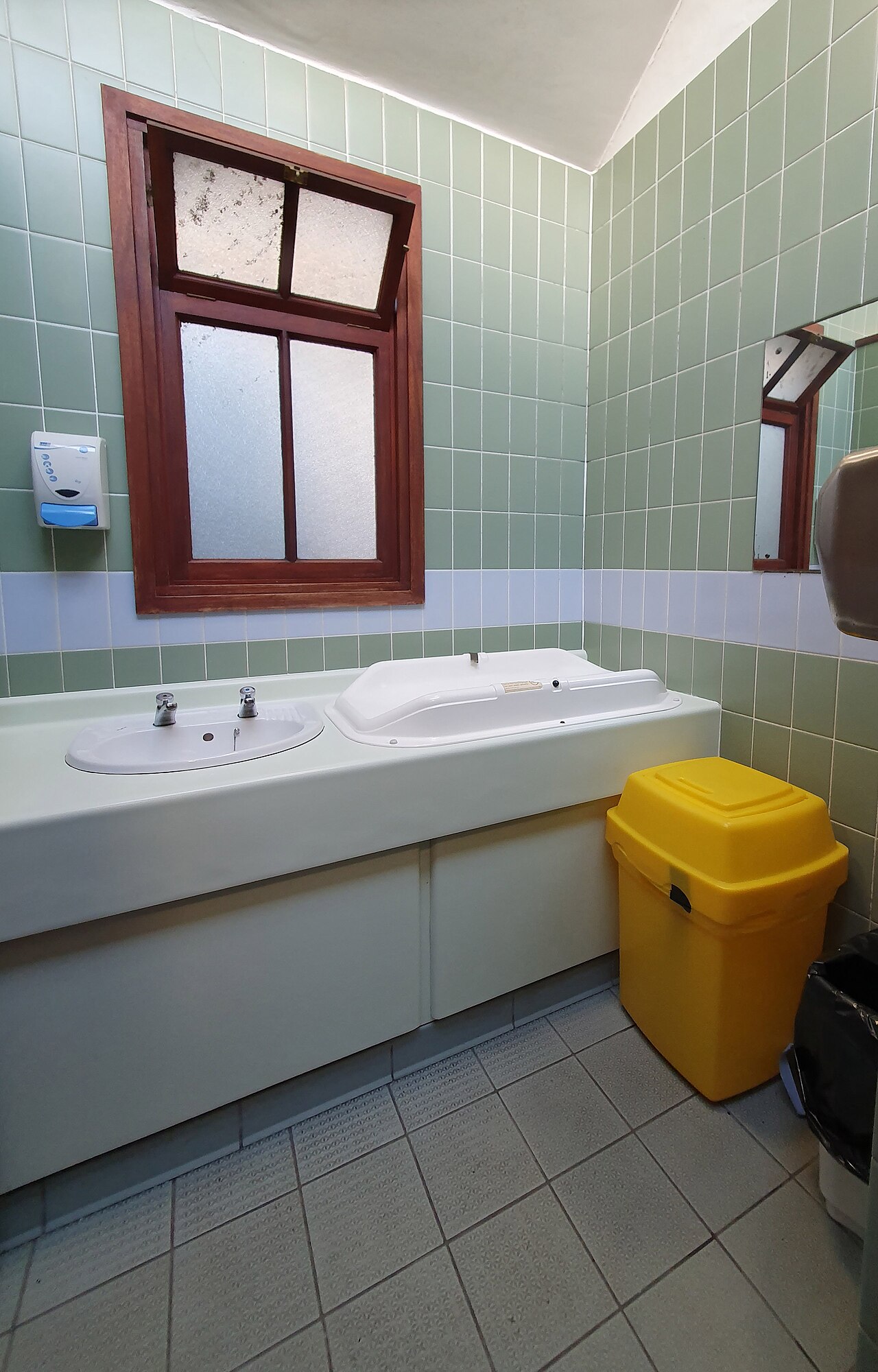 Een opklapbare luiertafel aan de muur van een openbaar toilet