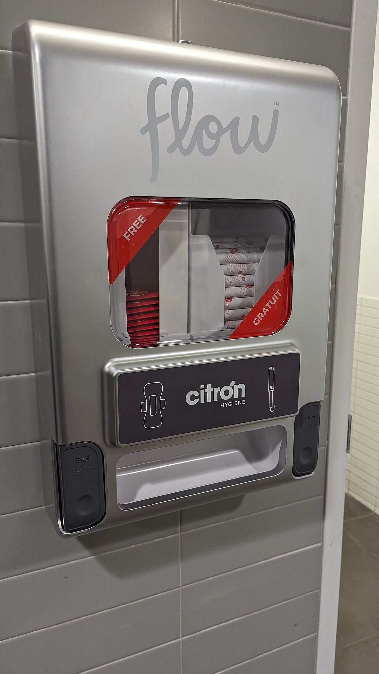 Een automaat met gratis maandverband en tampons aan de muur van een toilet