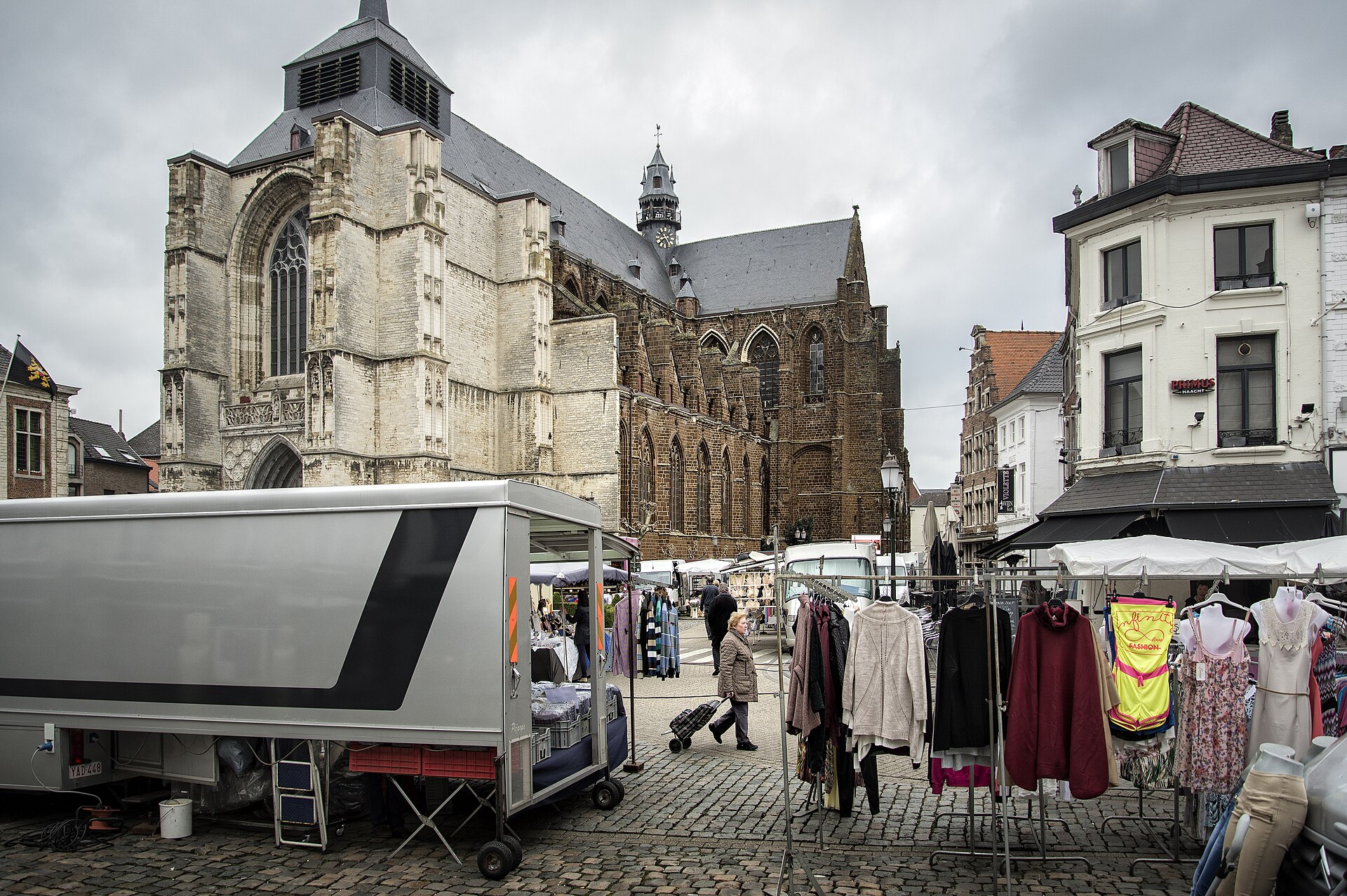 Marktdag op de Grote Markt van Diest, met kramen, kleerrekken en de kerk op de achtergrond