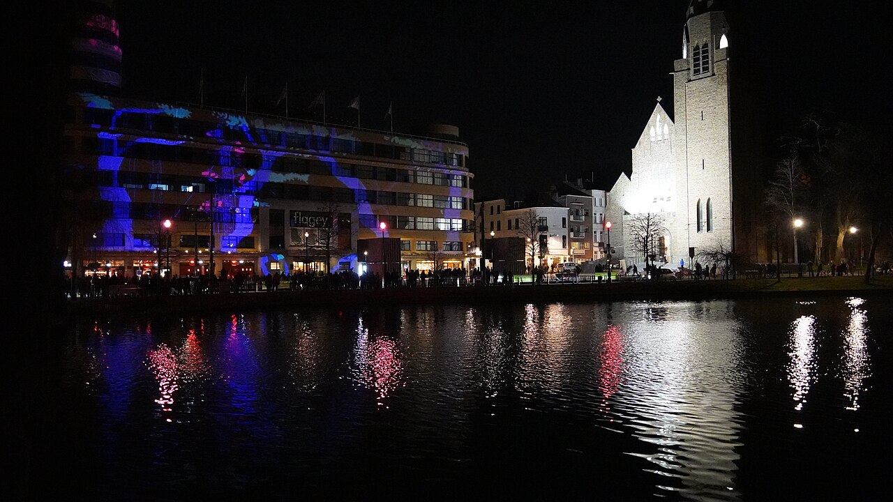 Een uitgaansplein in Brussel bij nacht, met verlichte gevels en mensen op straat