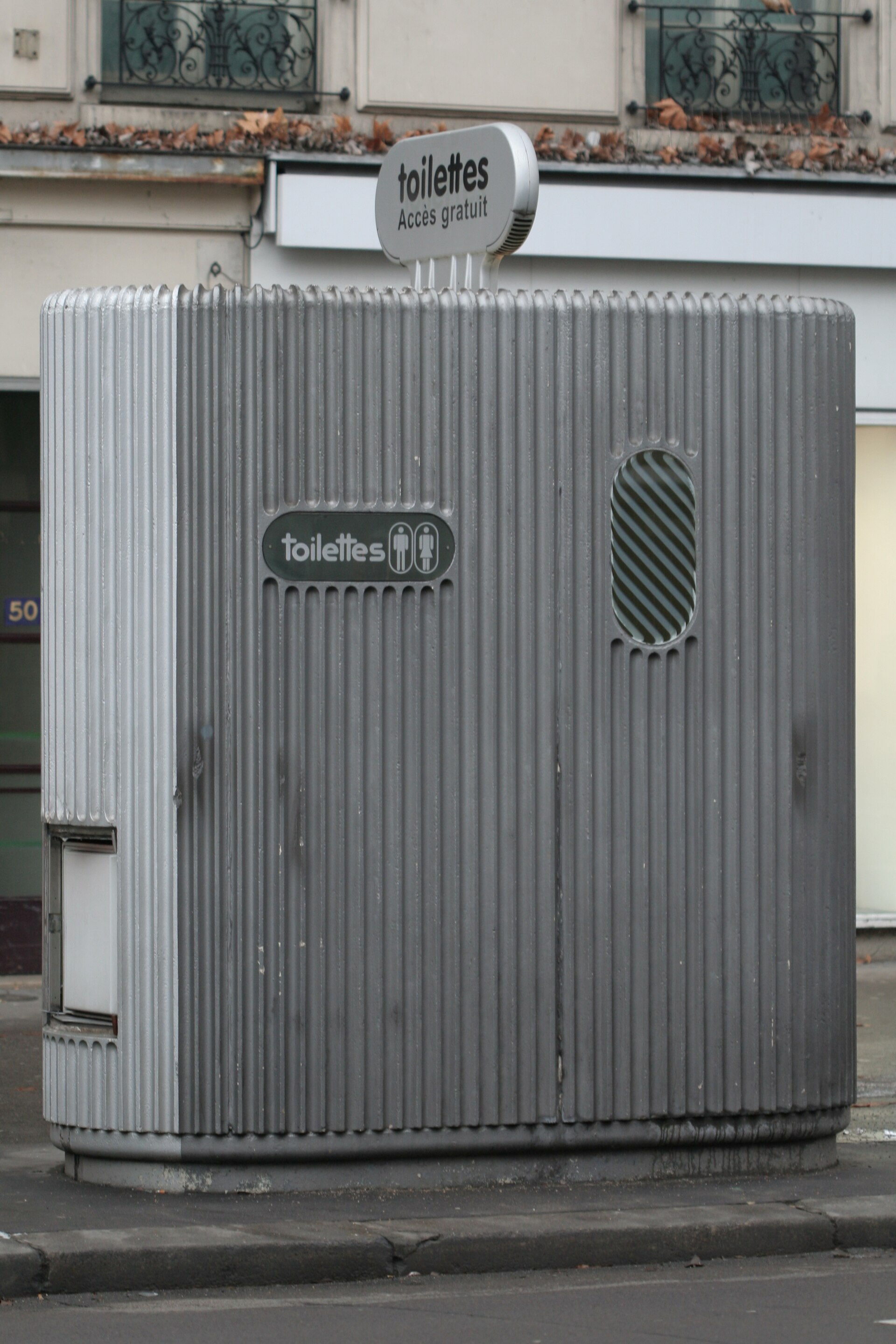 Een zelfreinigend straattoilet in Parijs, een geribde metalen cabine met het opschrift toilettes en accès gratuit