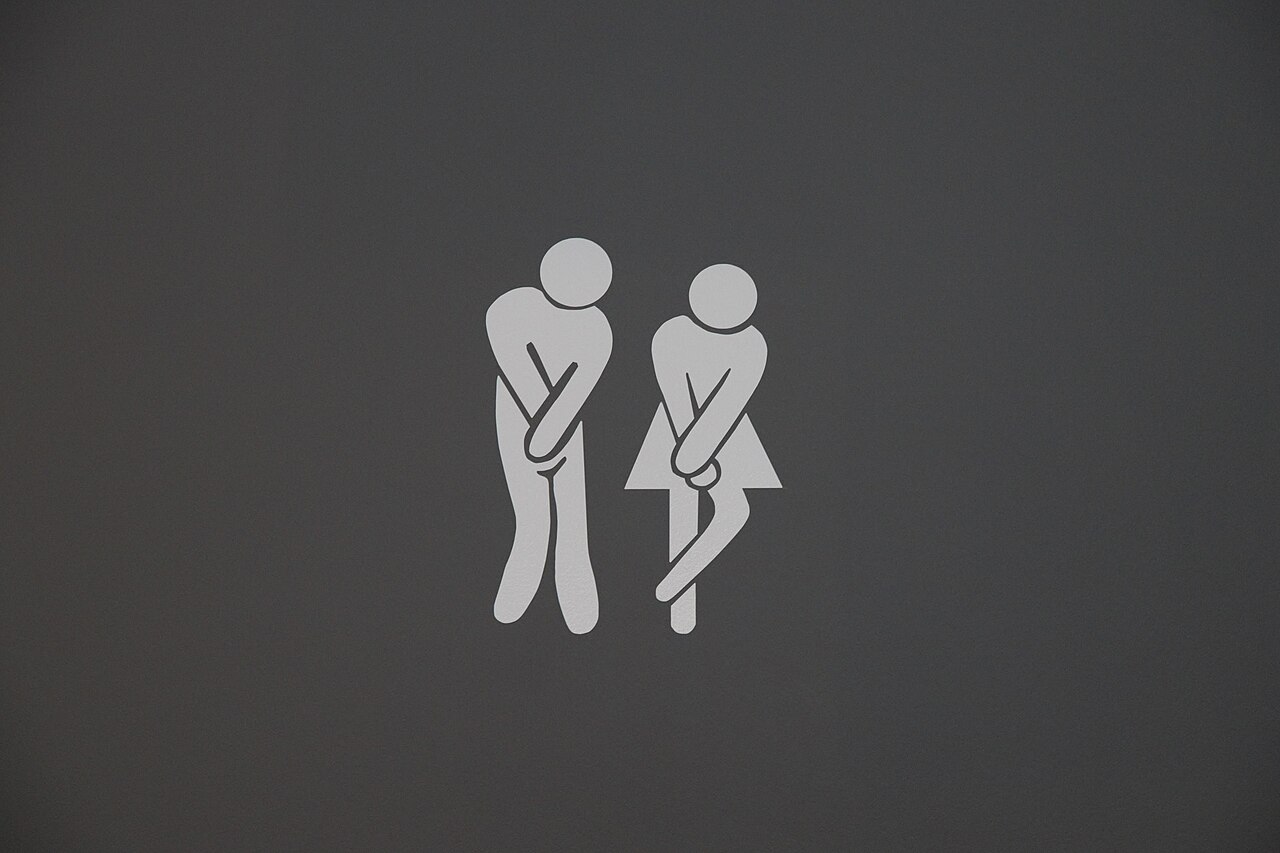 Toiletbordje met twee pictogrammen die met gekruiste benen staan te wachten