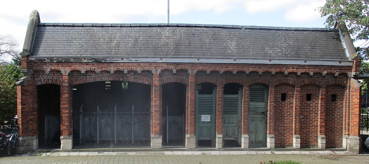 Een oud gemeentelijk toiletgebouw in rode baksteen met groene deuren